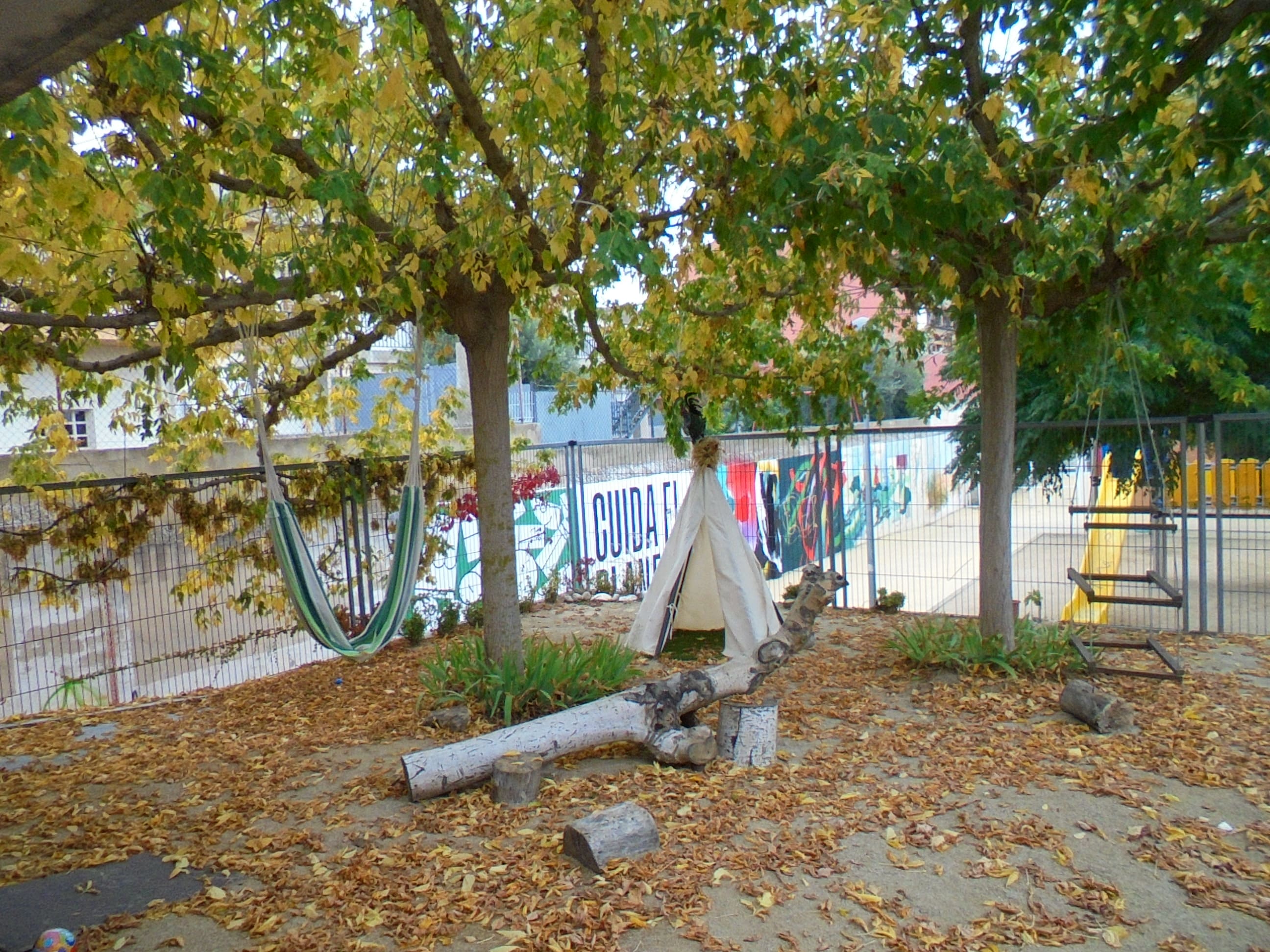 Espai del jardí on hi ha la tipi, l’hamaca de tela, el gronxador de fusta i alguns troncs que possibiliten diverses formes de joc. 