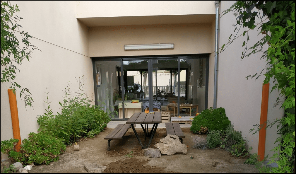 Taula de pícnic, envoltada de flors i plantes.